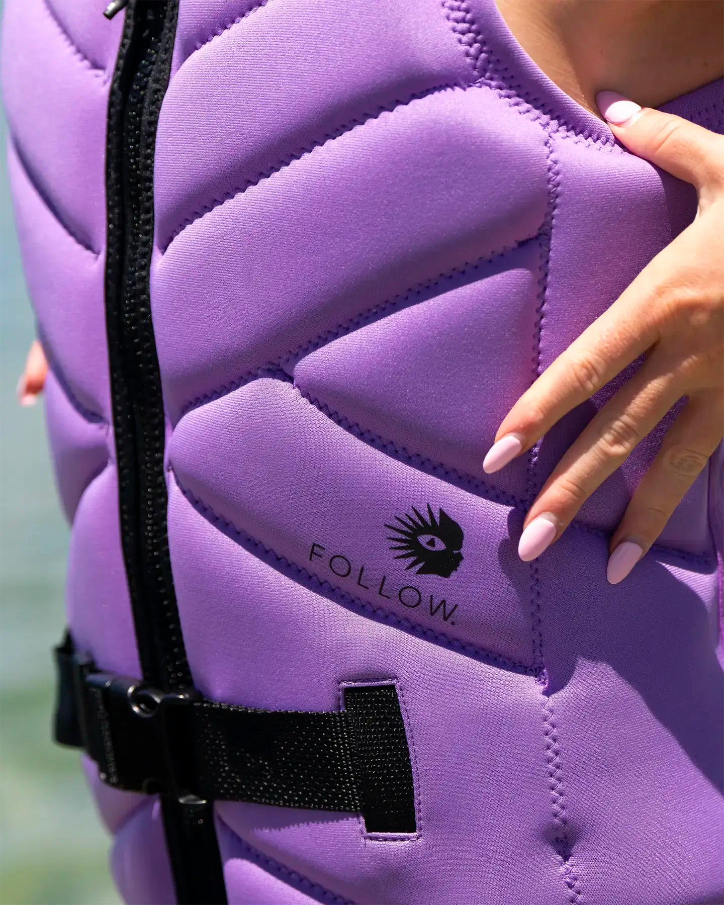 Purple protective life vest with 'FOLLOW' branding on a blurred background